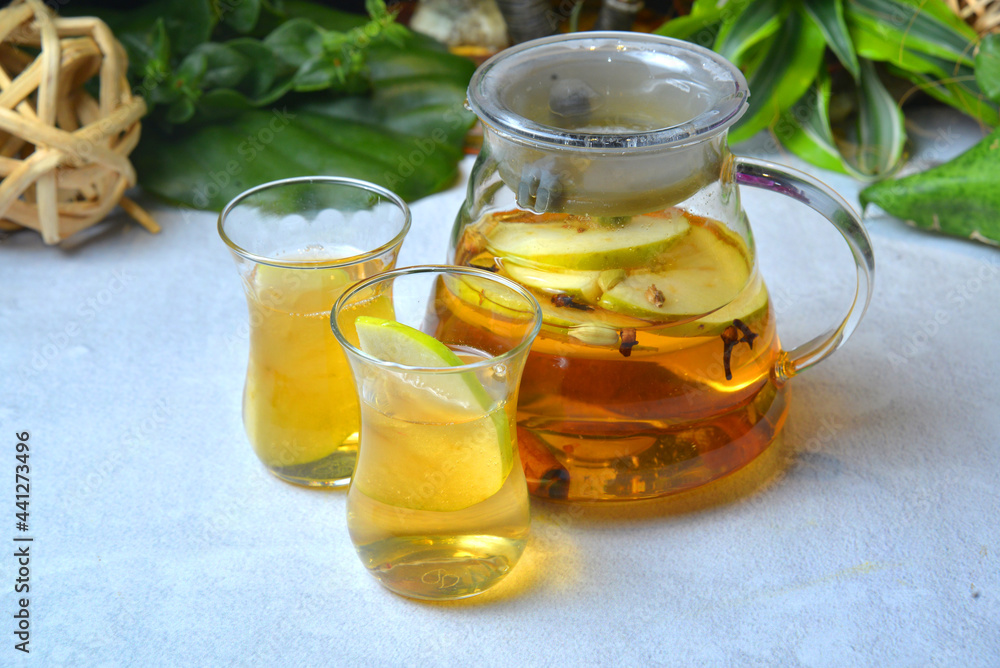 Herbal tea with juce cranberries, apple, ginger, lemon, cinnamon and thyme in a jar. Warming tea, healthy fruit infused tea. Horizontal closeup view on tropical background- Image Herbal tea with juce cranberries, apple, ginger, lemon, cinnamon and thyme in a jar. Warming tea, healthy fruit infused tea. Horizontal closeup view on tropical background- Image