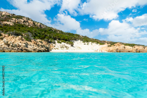  Selective focus  Defocused white sand beach in the background bathed by a beautiful turquoise sea in the foreground. Isola di Spargi  Maddalena Archipelago  Sardinia  Italy.