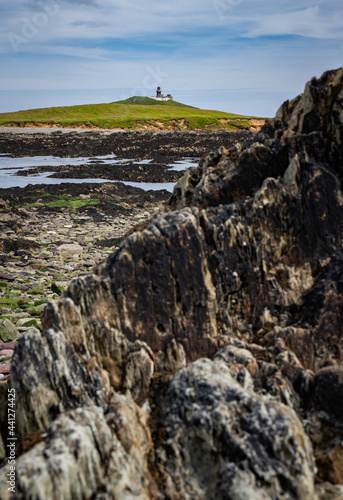 View of Ballycotton Lighthouse from rocky coast, county Cork, Ireland photo