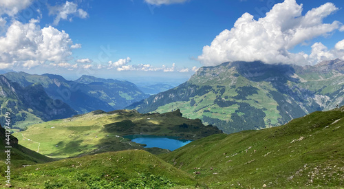 Beautiful lake surrounded by high mountains. Landscape in the swiss alps. Gorgeous green peaks with a blue sky in the background. 