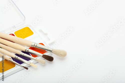 A set of watercolor paints and paint brushes on a white background with a copy space for text