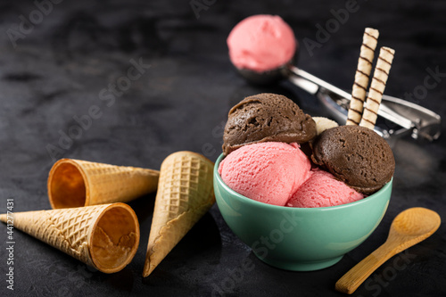 Bowl with Neapolitan ice cream on dark background. photo