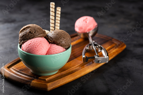 Bowl with Neapolitan ice cream on dark background. photo