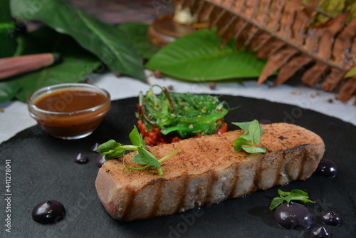 Grilled Tuna Fish Fillet with chuka salad served on black round plate - Image