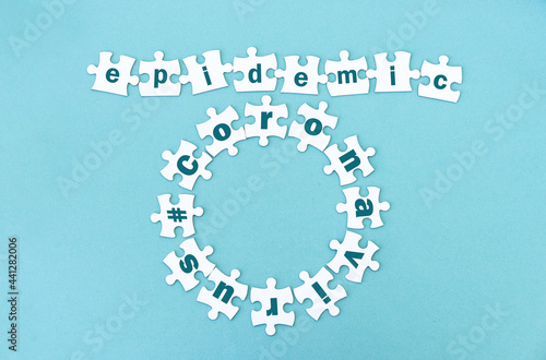 Circle and row made of white jigsaw puzzle pieces with word epidemic andcoronavirus on blue photo