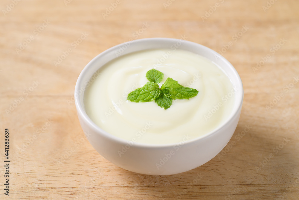 Yogurt in a bowl with mint leaf on wooden background, Healthy food Yogurt in a bowl with mint leaf on wooden background, Healthy food