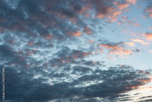 fotografia del cielo tormentoso y tranquilo con nubes cumulus estractus azules, blancas, naranjas y negra , con un molino de agua de fondo, horizontal apaisado. photo