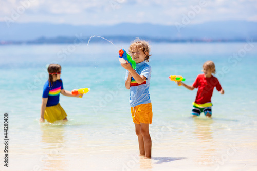 Child with toy water gun. Kids vacation beach fun. photo