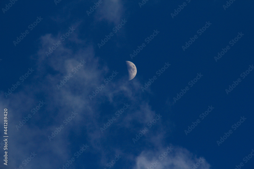 Moon in metallic blue sky with clouds Moon in metallic blue sky with clouds