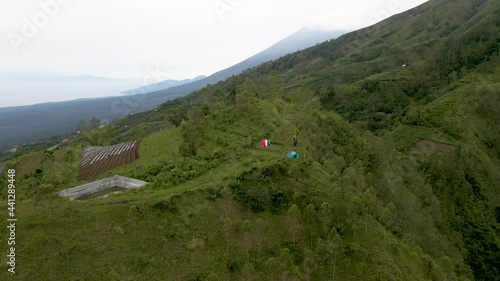 People exploring Bali and camping a top green ridge in Bali. Drone wide view photo