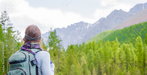 Young woman with backpack enjoys the view of nature at hike. Empty space for text © Ermolaev Alexandr