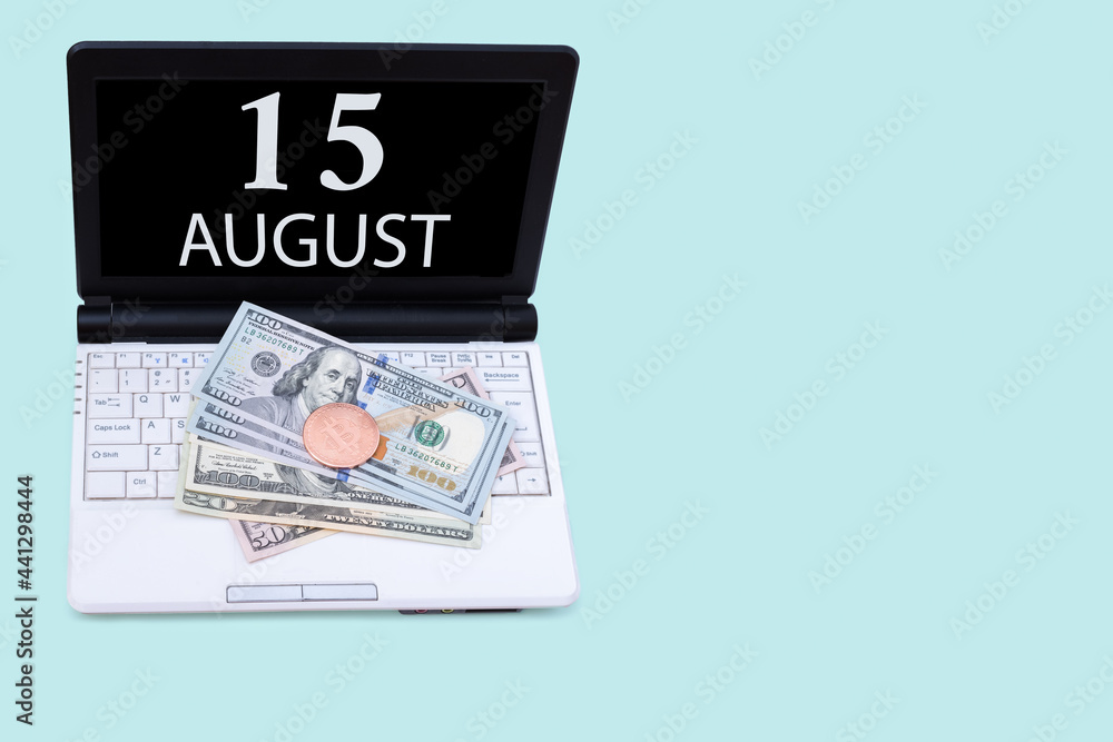 Obraz premium Laptop with the date of 15 august and cryptocurrency Bitcoin, dollars on a blue background. Buy or sell cryptocurrency. Stock market concept.