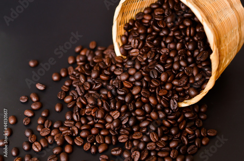 basket of coffee beans poured on the wooden plank and Black background