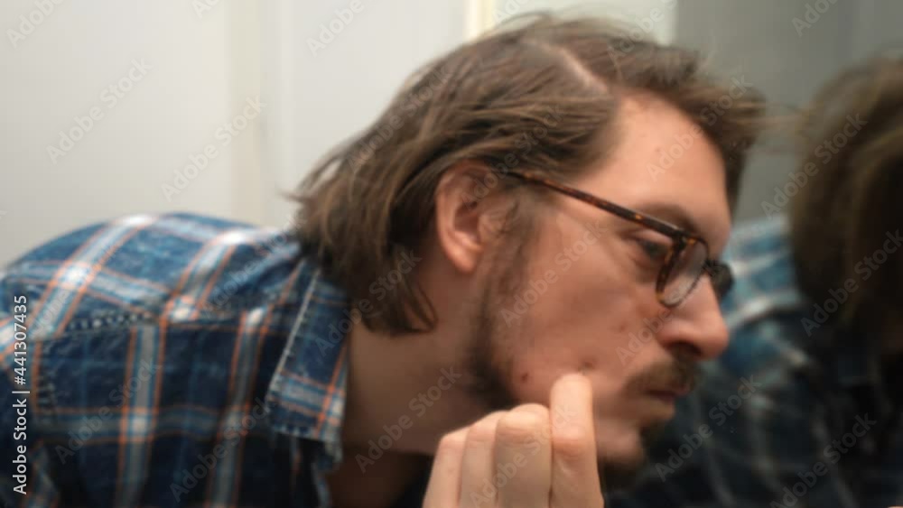 View of a Man in a Mirror Picking up his face with Tweezers, marks and scars View of a Man in a Mirror Picking up his face with Tweezers, marks and scars