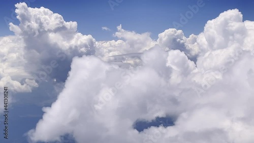 View from airplane window flying through the clouds high in the sky.