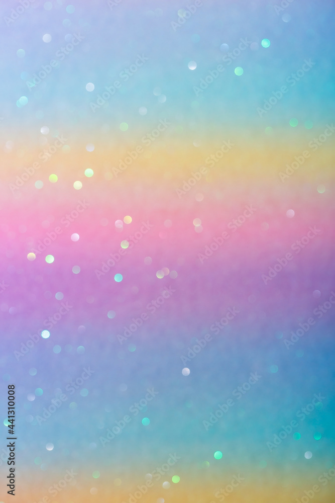 Photo of a rainbow-colored paper surface with glitter. Abstract blurred multi-colored pastel background with sequins