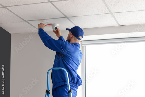 Worker installing alarm system indoors