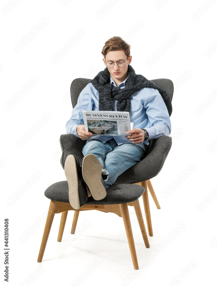 Young man reading newspaper while sitting in armchair on white background