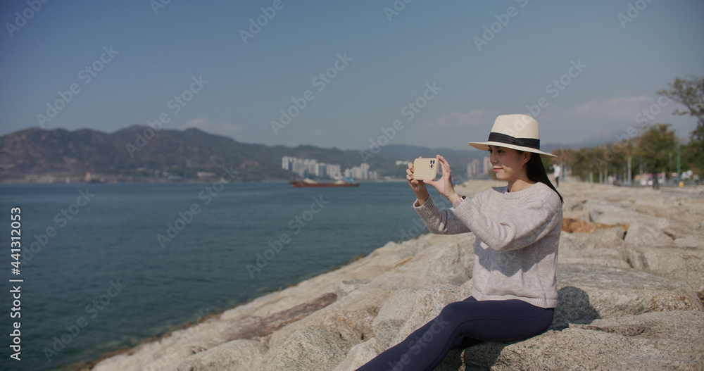 Woman use cellphone to take photo at seaside