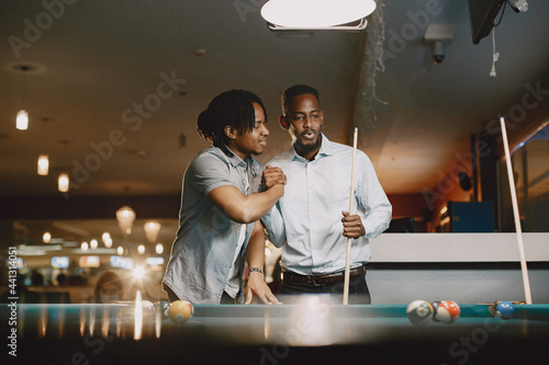 Men playing billiards in a club photo
