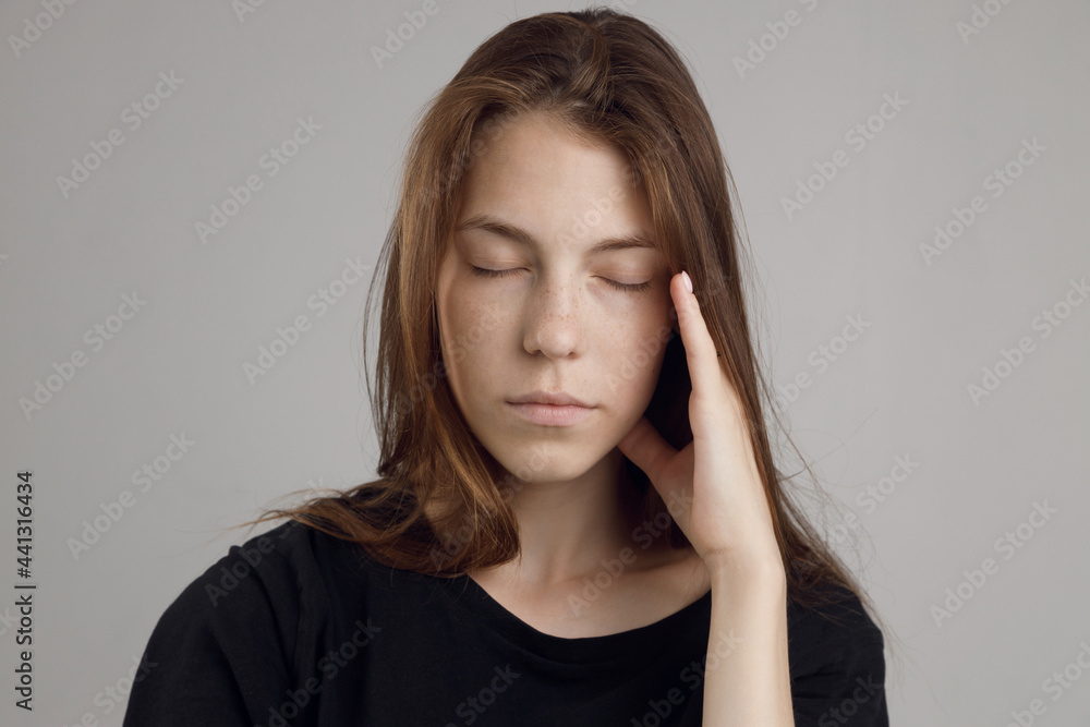 A young woman with a headache, holding her head, isolated on a white background. Portrait of a girl, medical theme, pain in the temples. A young woman with a headache, holding her head, isolated on a white background. Portrait of a girl, medical theme, pain in the temples.