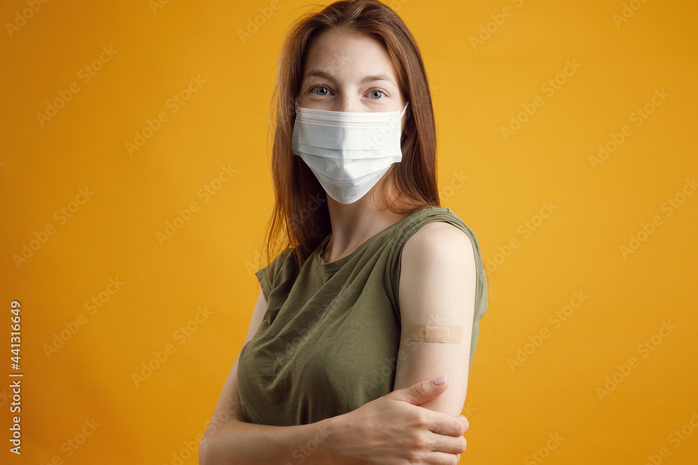 A happy girl on a yellow empty background in the studio, smiling and showing her hand after the injection of the vaccine. Coronavirus, Ncov-19, vaccination and immunization against influenza. A happy girl on a yellow empty background in the studio, smiling and showing her hand after the injection of the vaccine. Coronavirus, Ncov-19, vaccination and immunization against influenza.