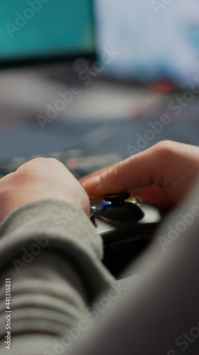 Close up on hands of video game r playing using wireless joystick in cyberspace sitting on gaming chair. Cyber man holding controller performing space shooter video games at online esports