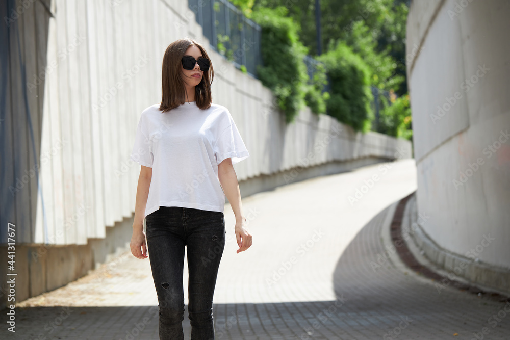 Fototapeta premium Girl or woman wearing white blank t-shirt with space for your logo, mock up or design in casual urban style
