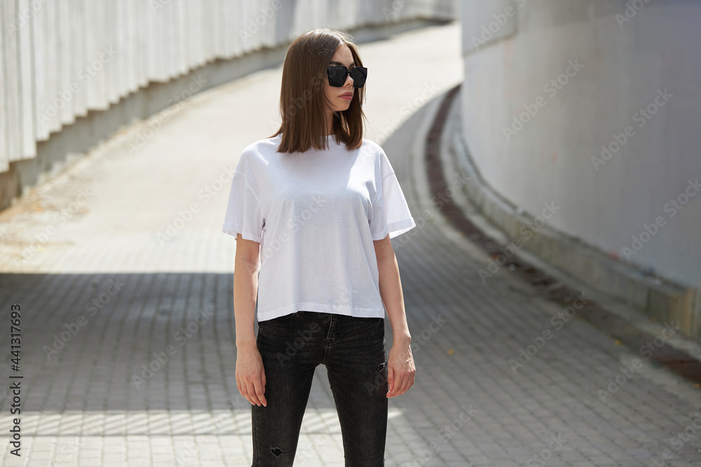 Fototapeta premium Girl or woman wearing white blank t-shirt with space for your logo, mock up or design in casual urban style