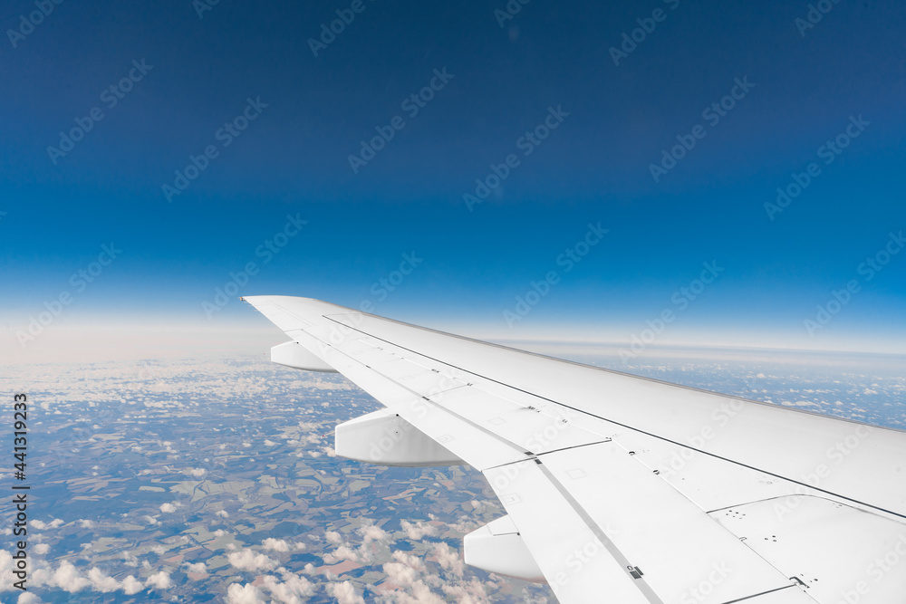 Fototapeta premium Wing of passsanger plane above the land, view from inside