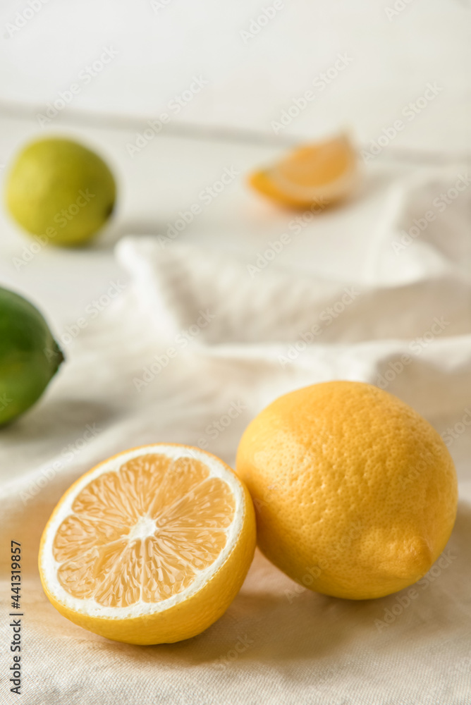 Healthy lemons and limes on light fabric background