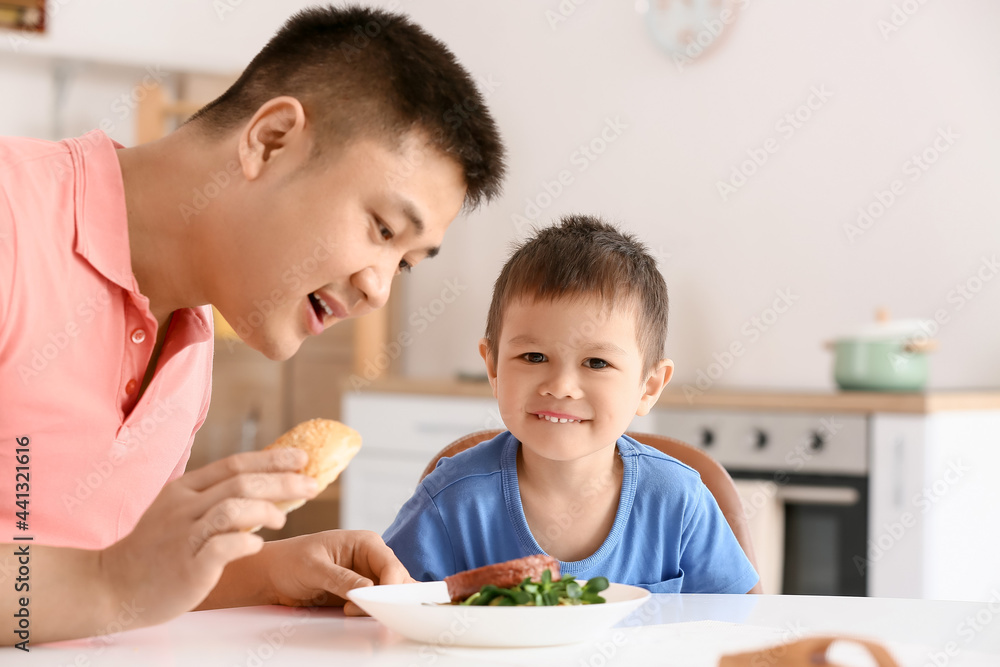 Father feeding his little son in kitchen