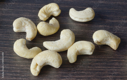 Several cashew nuts are scattered on a dark table photo