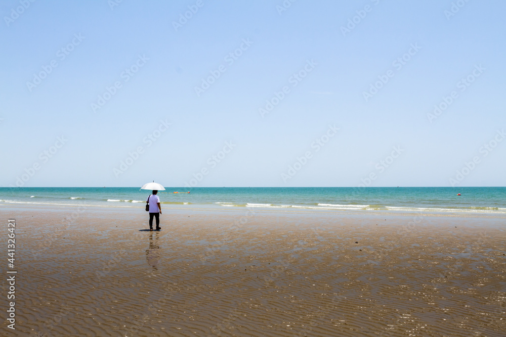 Asian woman with white umbrella walking relax on the beach