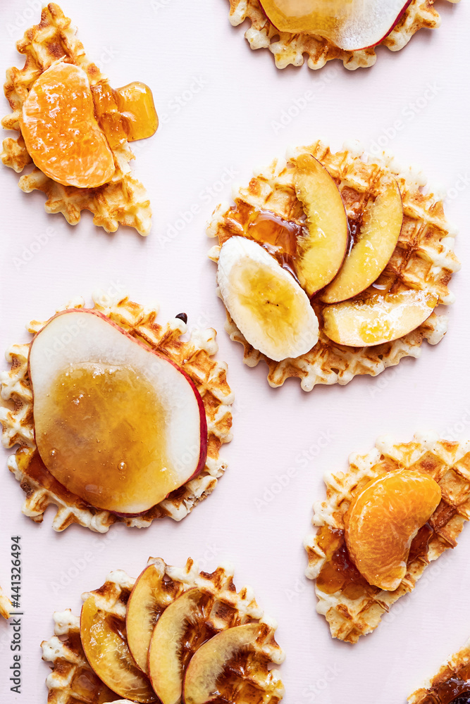 Belgian traditional waffles with various topping. Flat lay of waffles with honey and slice of various fruits. Sweet food, dessert background.