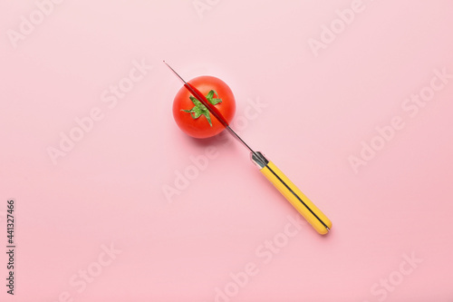 Fresh ripe tomato with knife on color background