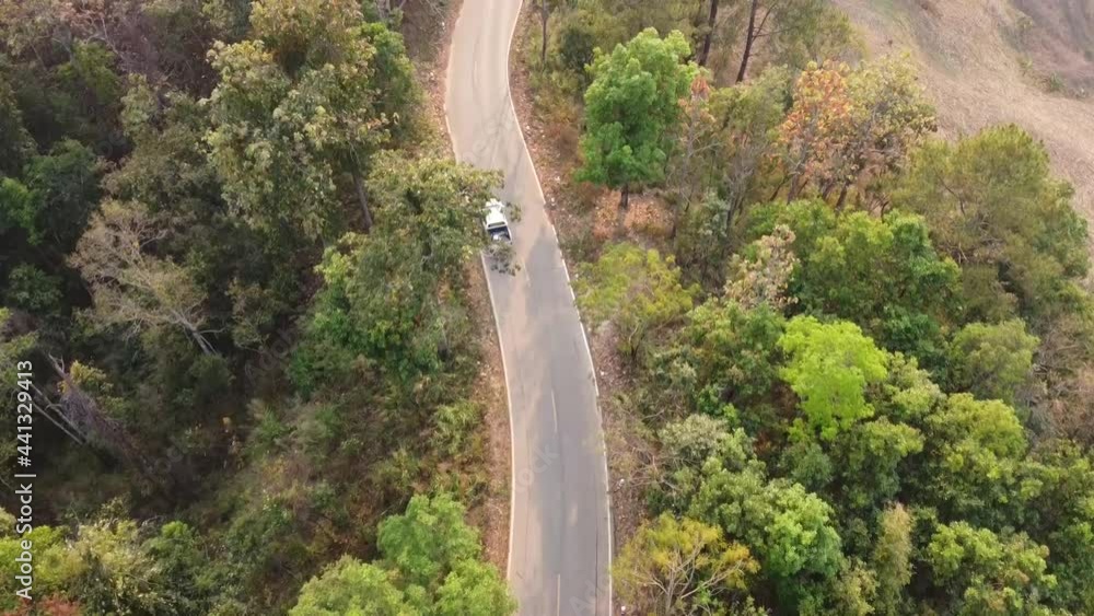 aerial view The white car traverses the beautiful landscape mountains lush forests and greenery on either side aerial view The white car traverses the beautiful landscape mountains lush forests and greenery on either side