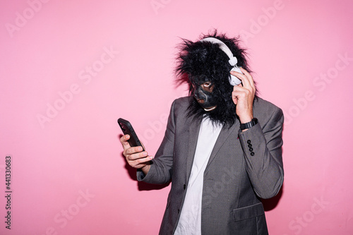 Gesture man with gorilla mask and headphones using smart phone photo