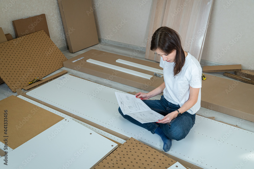 Woman Reading Assemble the furniture Manual in home. Move into New House Woman Reading Assemble the furniture Manual in home. Move into New House