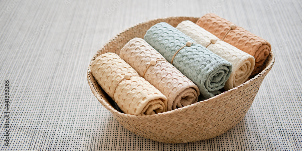 Collection of natural muslin bath towels in a wicker basket on the floor. Natural, soft, air and stylish home textiles. View from above.