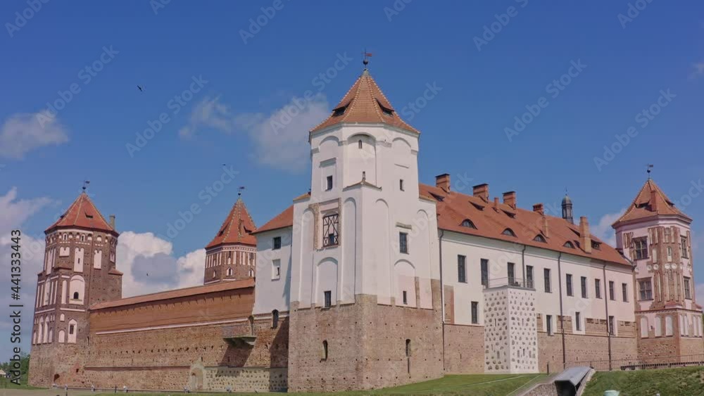 Mir castle with spires near the lake. View of Mir castle, Belarus. Park complex Mir. Old deserted castle. Aerial low angle view. Mir castle with spires near the lake. View of Mir castle, Belarus. Park complex Mir. Old deserted castle. Aerial low angle view.