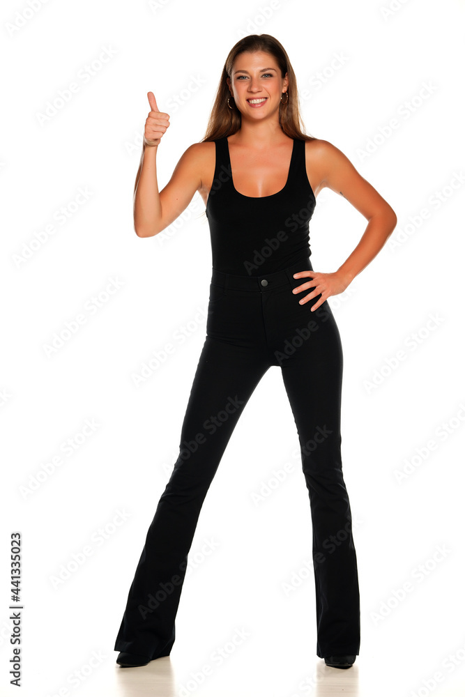 a young beautiful smiling woman in pants and a shirt showing thumbs up a young beautiful smiling woman in pants and a shirt showing thumbs up