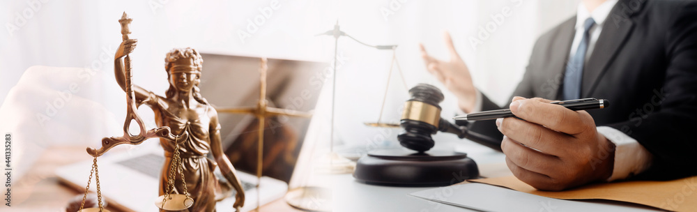 Justice and law concept.Male judge in a courtroom with the gavel, working with, computer and docking keyboard, eyeglasses, on table in morning light Justice and law concept.Male judge in a courtroom with the gavel, working with, computer and docking keyboard, eyeglasses, on table in morning light