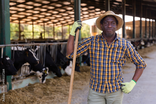 Portrait of confident young adult man farmer posing on dairy farm