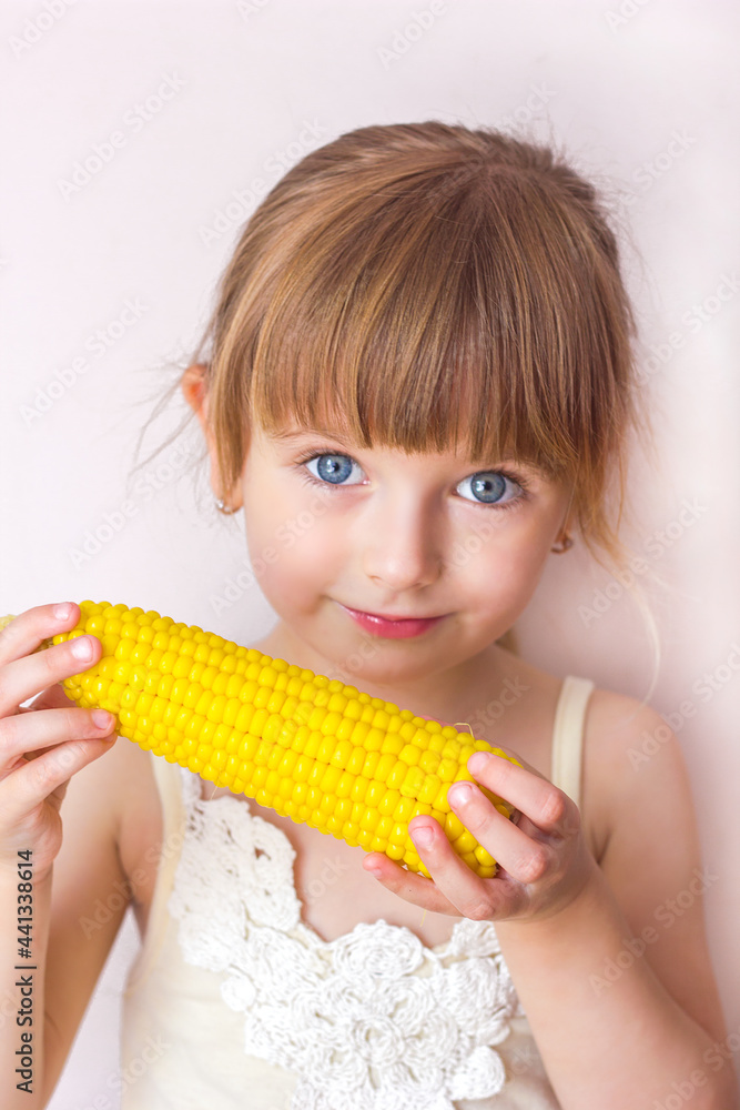Close-up portrait of a little beautiful girl with blue eyes and boiled corn in her hands Close-up portrait of a little beautiful girl with blue eyes and boiled corn in her hands