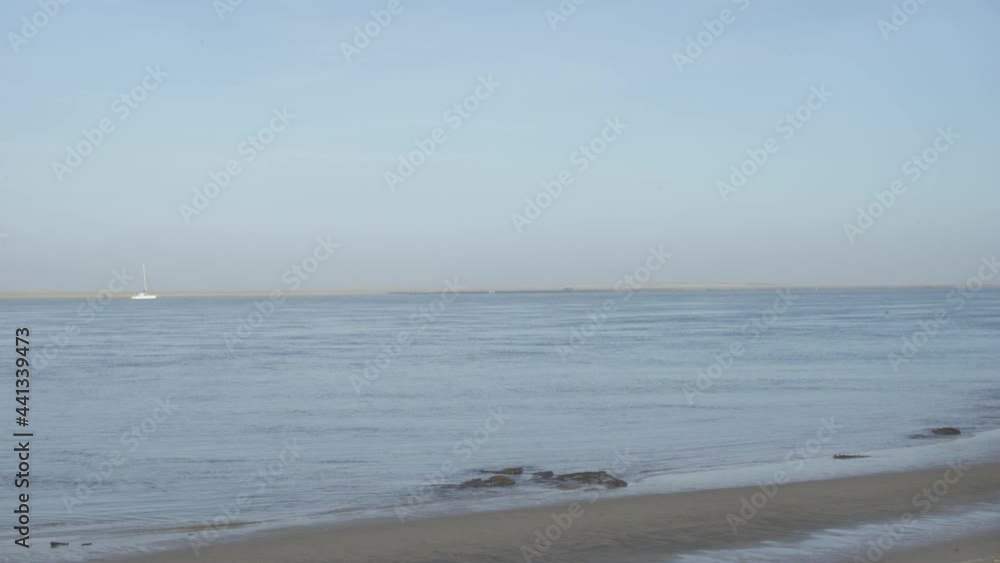 A white sailboat highlighted by the sunlight on the coast of Marseille, France - wide shot