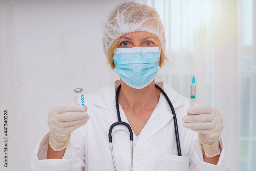 Doctor with mask and syringe is ready to administer the vaccine against covid 19