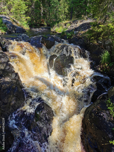 A picturesque waterfall on the Tokhmayoki River in Karelia surrounded by trees on a clear summer morning. photo