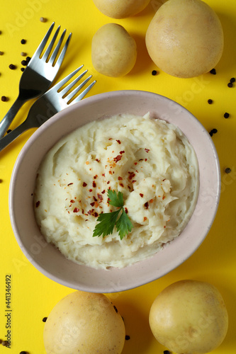 Plate of mashed potatoes and ingredients on yellow background