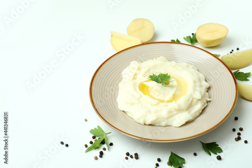 Plate of mashed potatoes and ingredients on white background